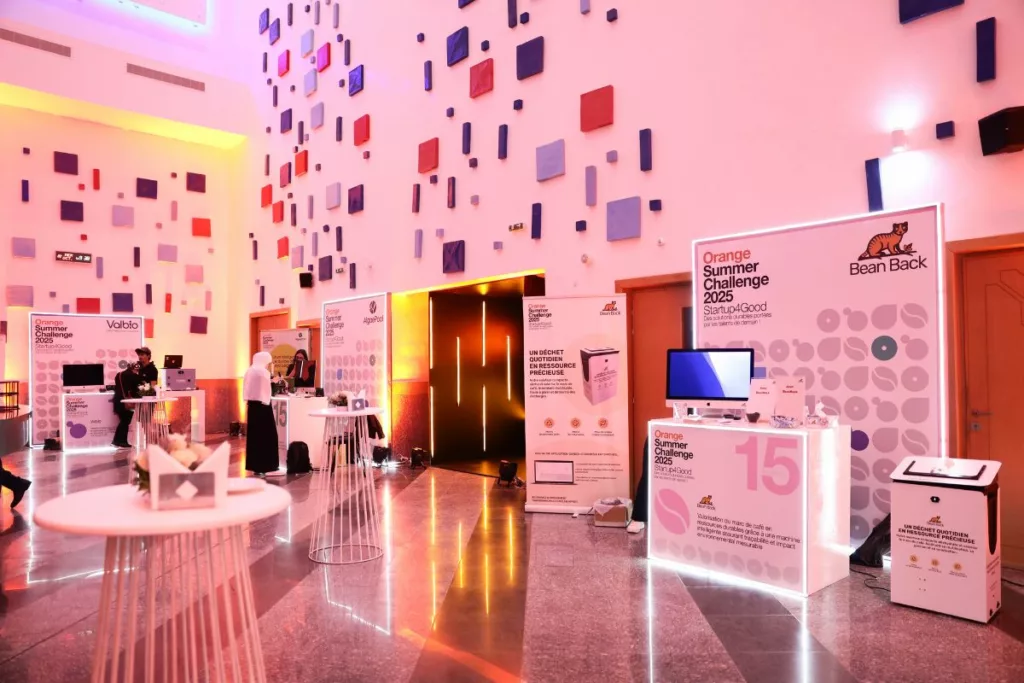 Salle polyvalente de l’Orange Summer Challenge 2025 avec les participants et les stands des porteurs de projets.